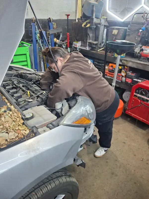Co-owner Ashley Adams working under the hood of a car at the Tough Knuckles Automotive shop in Holland, Ohio